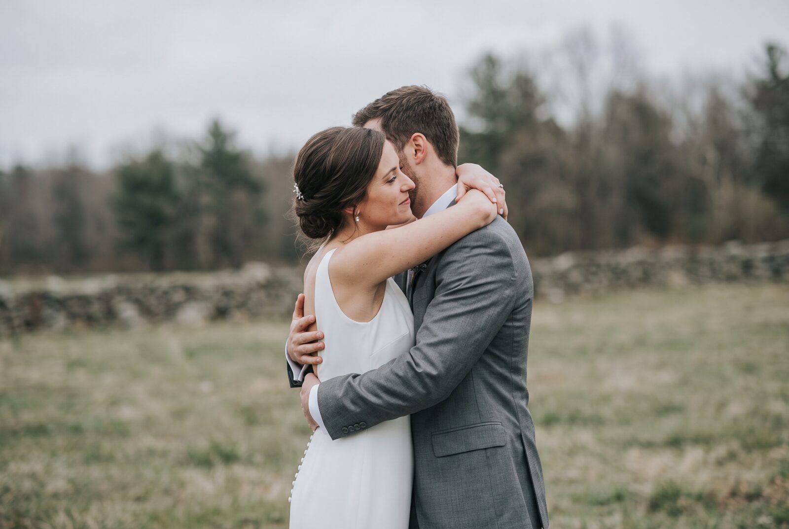 A bride and groom embracing outdoors in soft overcast daylight