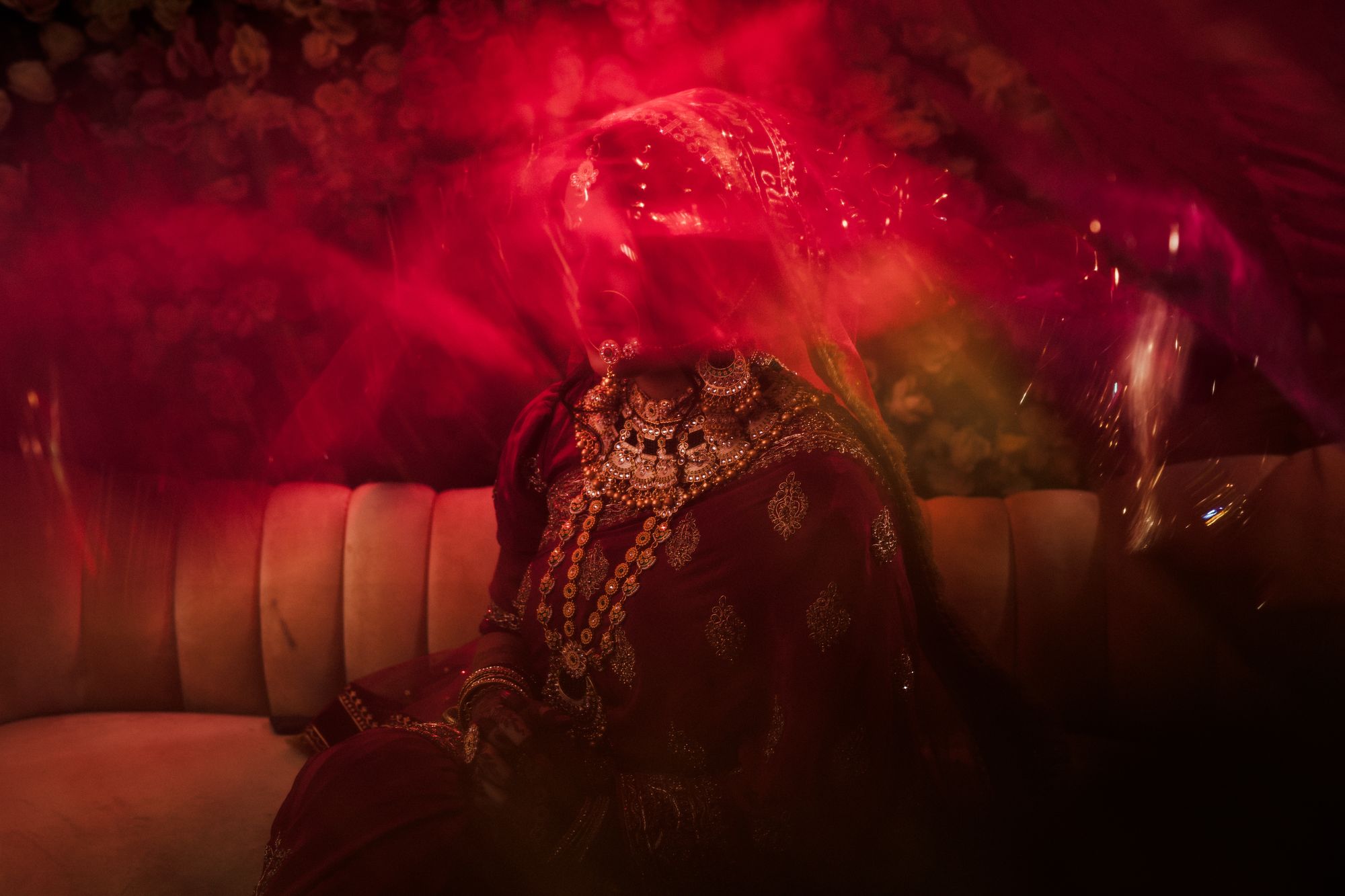 A bride in red bridal wear lit by deep red light