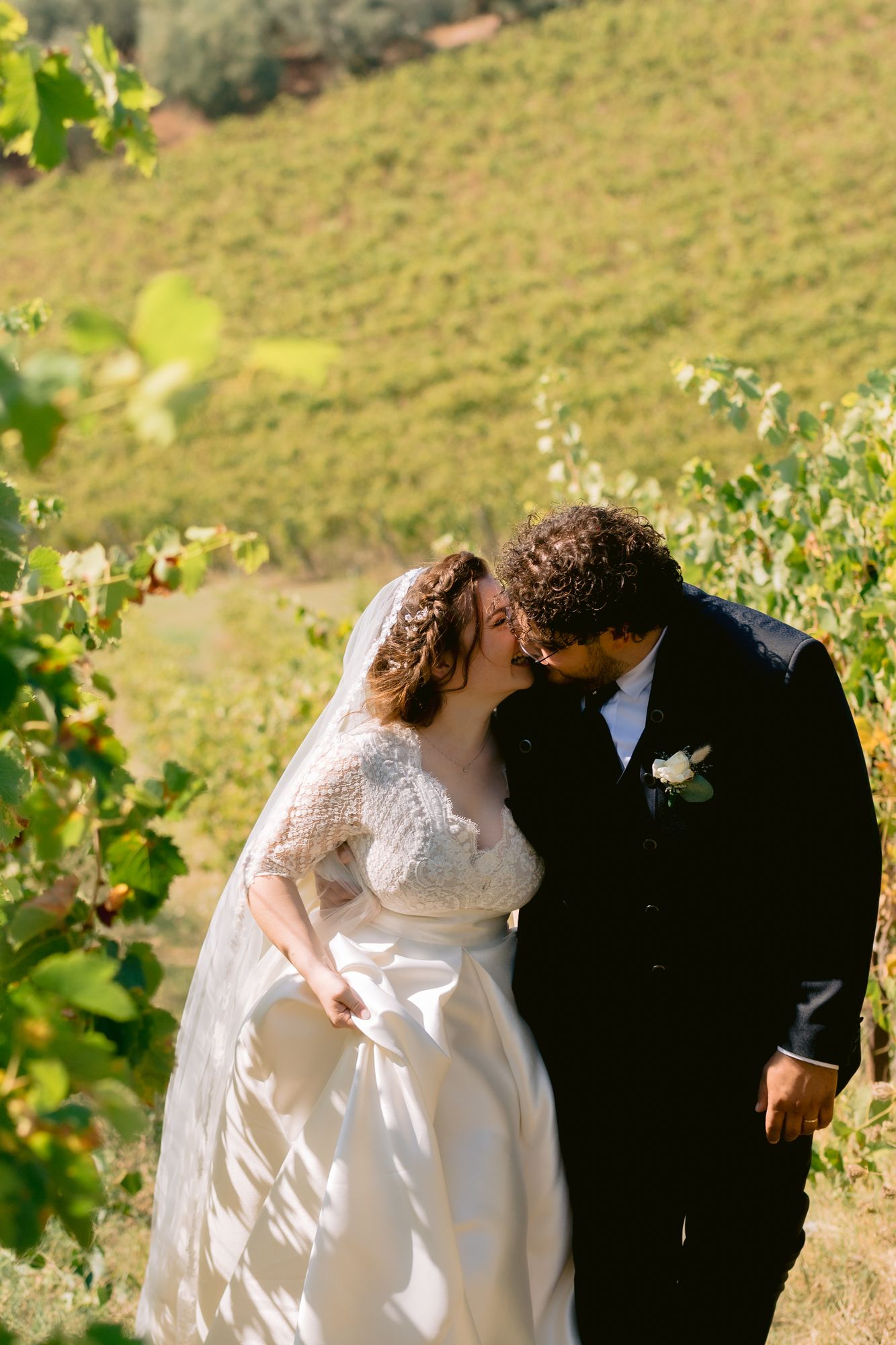 A bride and groom kissing among green vines